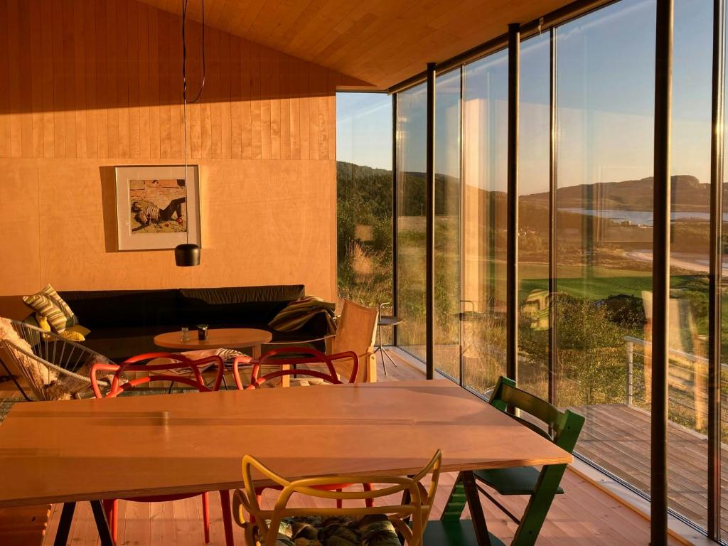 a room with tables and chairs and large windows at Beachfront Cabin Overlooking The Coast in Hosen