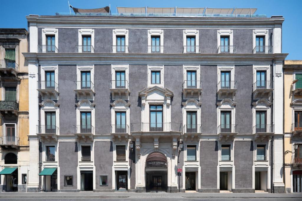 カターニアにあるPalace Catania | UNA Esperienzeのバルコニー付きの大きな灰色の建物