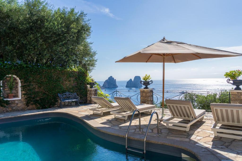 a group of chairs and an umbrella next to a swimming pool at Villa Danima in Capri