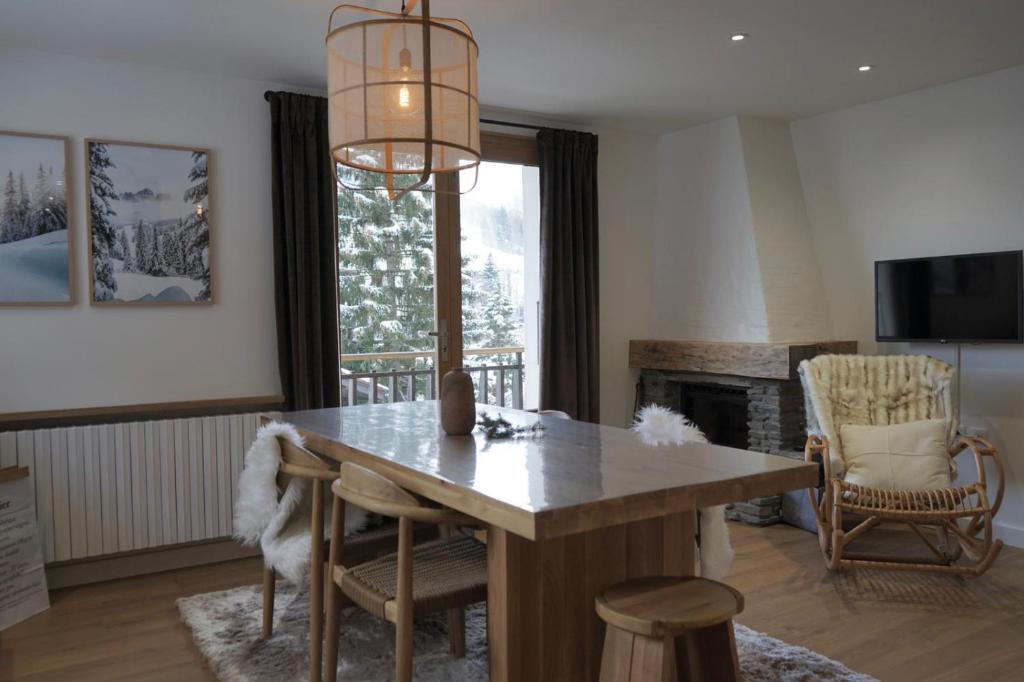 een eetkamer met een tafel en een open haard bij Muguets 4 in La Clusaz