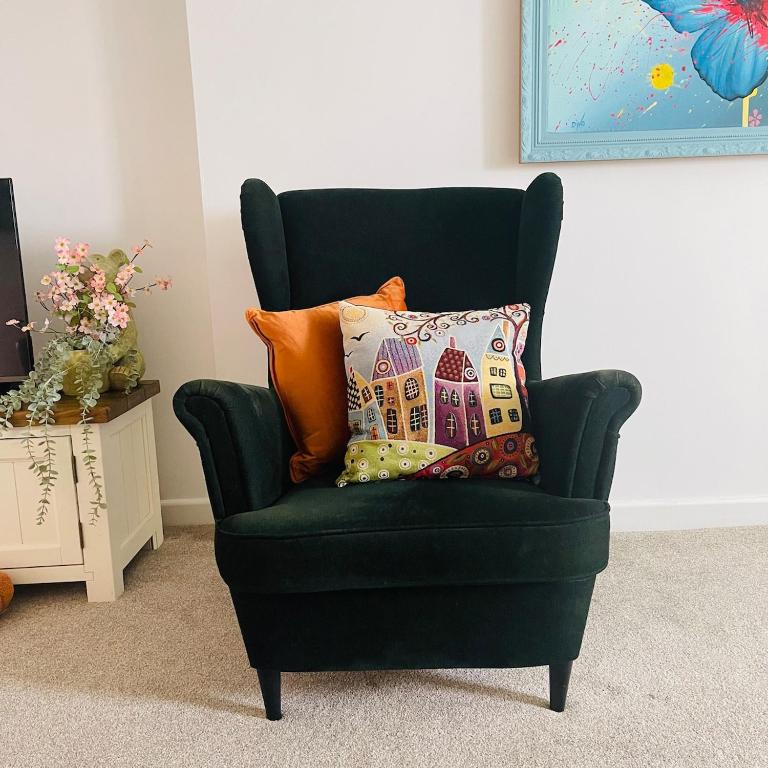a green chair with a pillow in a room at Bear Cottage - Waterfall Country in Glyn Neath
