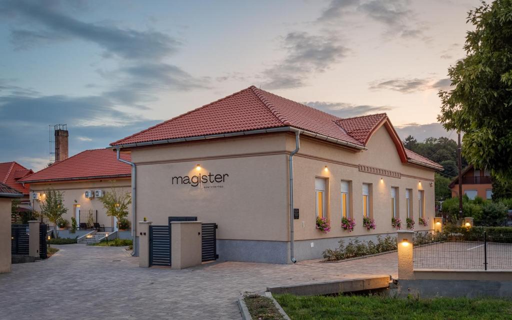 a building with a sign on the side of it at Magister Apartmanház in Cserépfalu