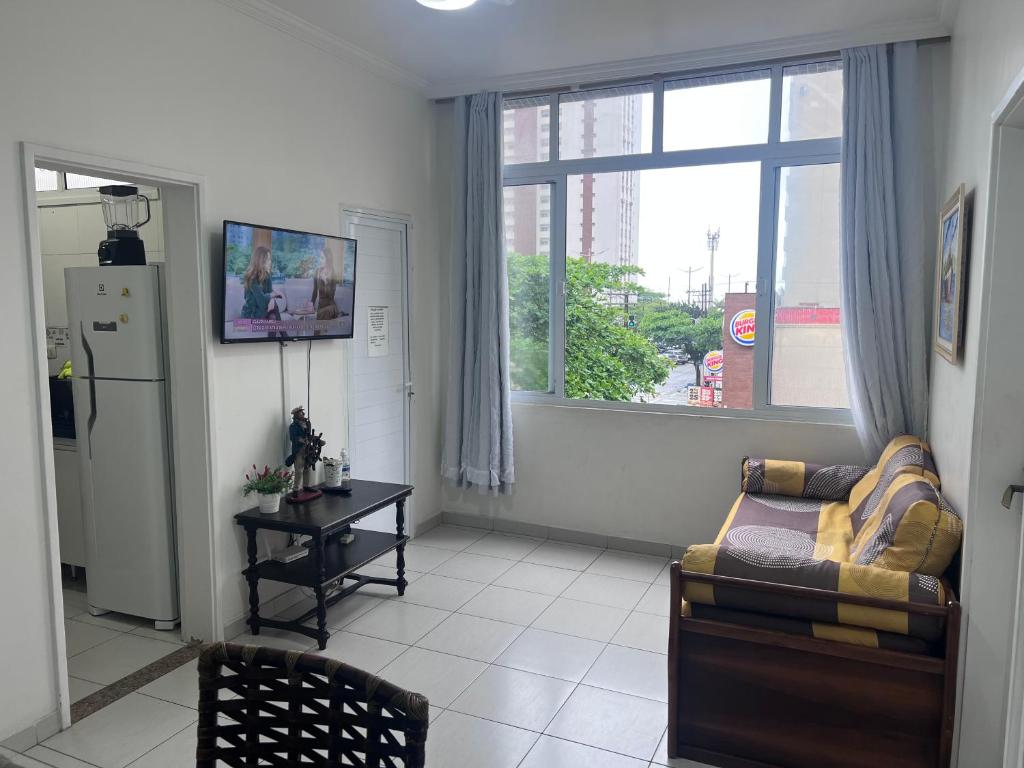 a living room with a couch and a large window at Apartamento 2 suítes Pitangueiras Guarujá in Guarujá