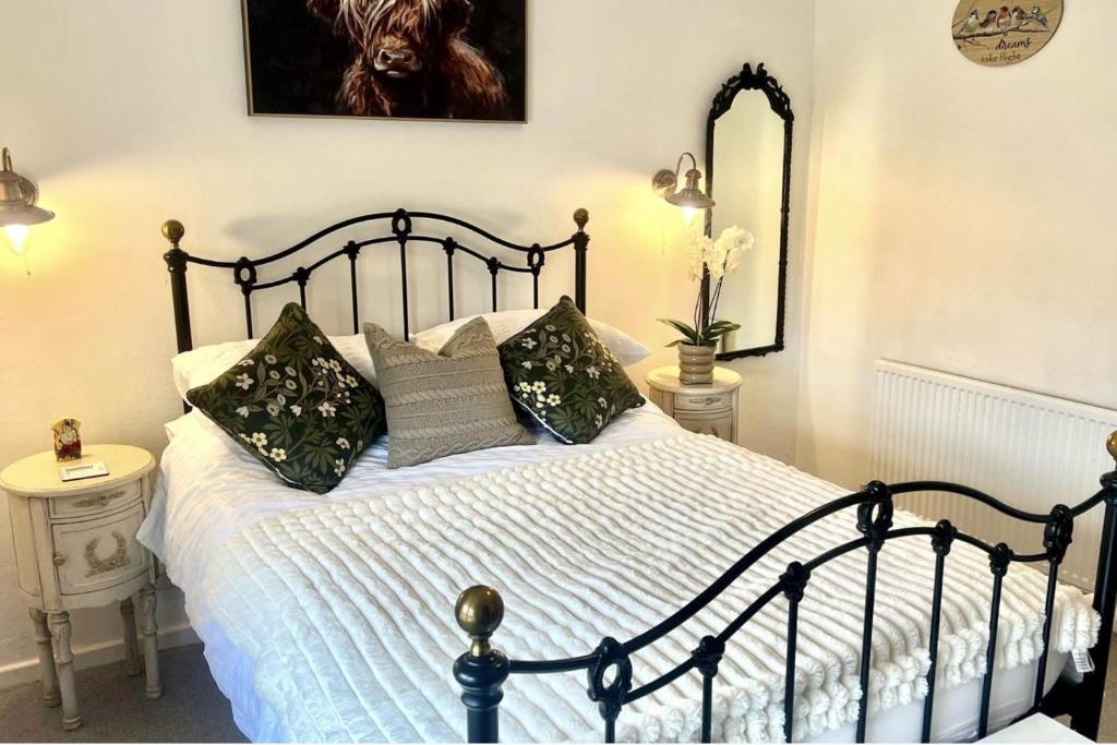 ein Schlafzimmer mit einem schwarz-weißen Bett mit Kissen in der Unterkunft 18th Century Cosy Cottage with Stunning Views in Stratford-upon-Avon