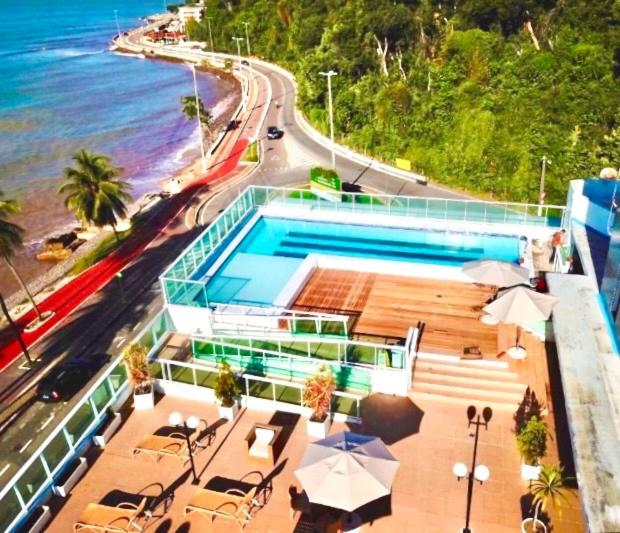 una piscina con tavoli e ombrelloni accanto all'oceano di Flat JP Beira mar a João Pessoa