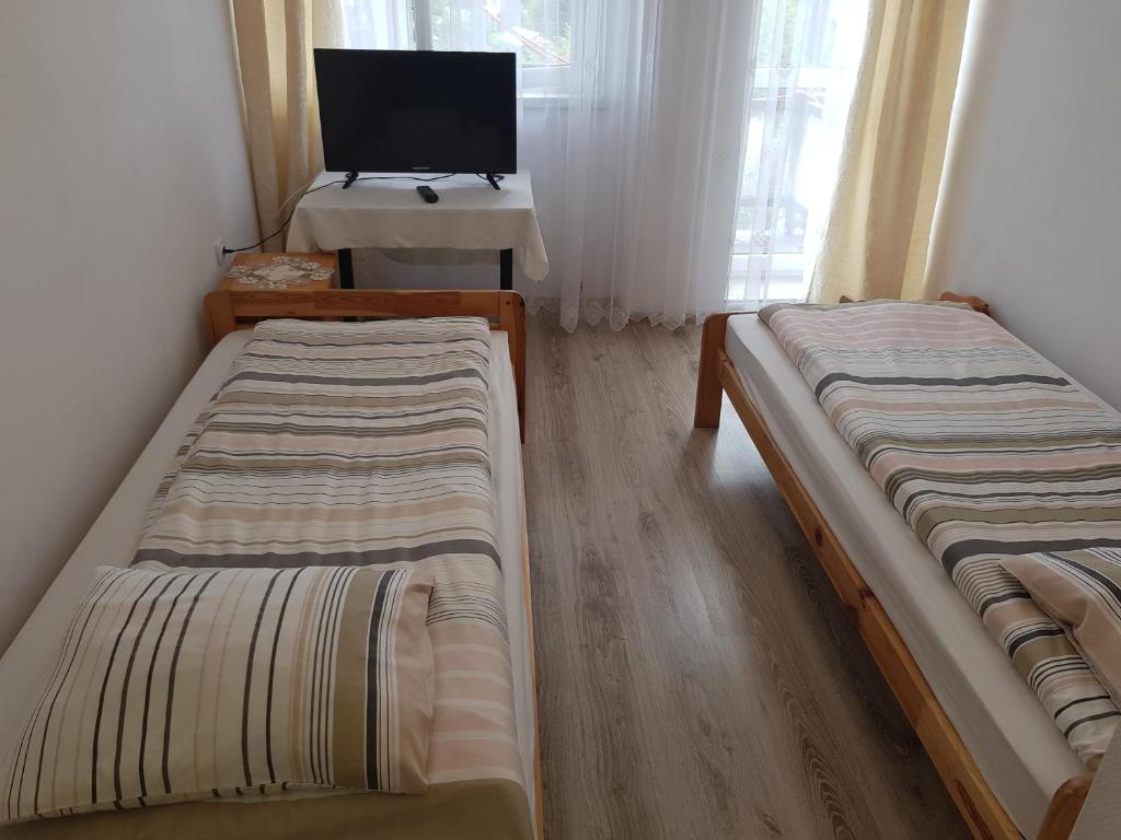 two beds in a room with a tv and a desk at Bobowianka in Bobowa