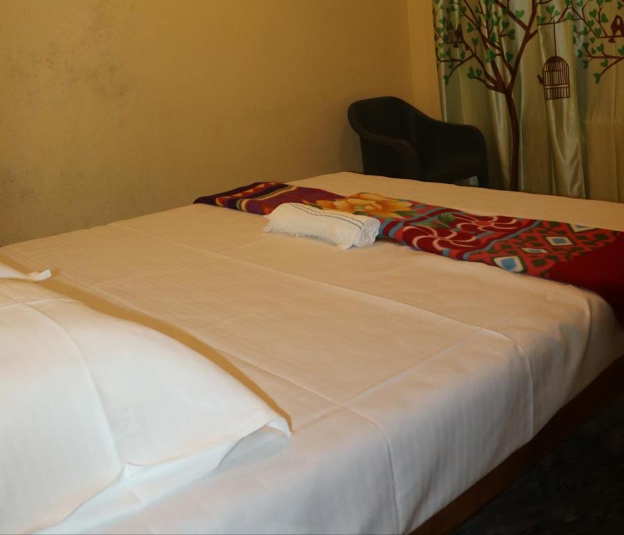 ゴカルナにあるKudle Heavenの白いシーツが敷かれた部屋にベッドが2つ
