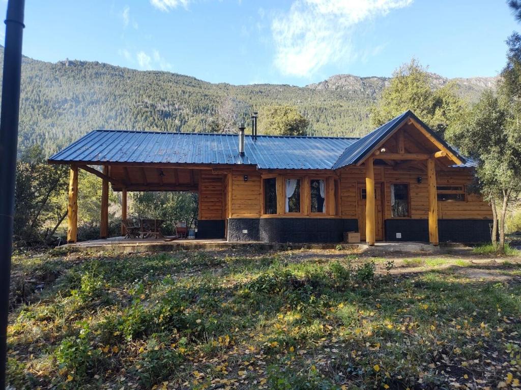 eine Blockhütte mit blauem Dach in der Unterkunft Lejana Casa de montaña in Lago Puelo