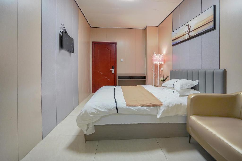 Un dormitorio con una cama, un televisor y un sofá. en UPTO Hotel, en Xiamen