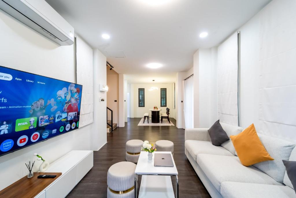 a living room with a white couch and a tv at Stylish 3 Bedroom Villa with Garden, Chalong - by PoshSaga in Chalong 