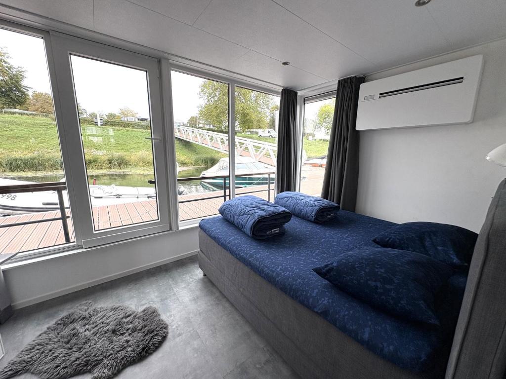 Un dormitorio con una cama con almohadas azules y una ventana. en De Maasterp - Woonboot 2, en Montfort