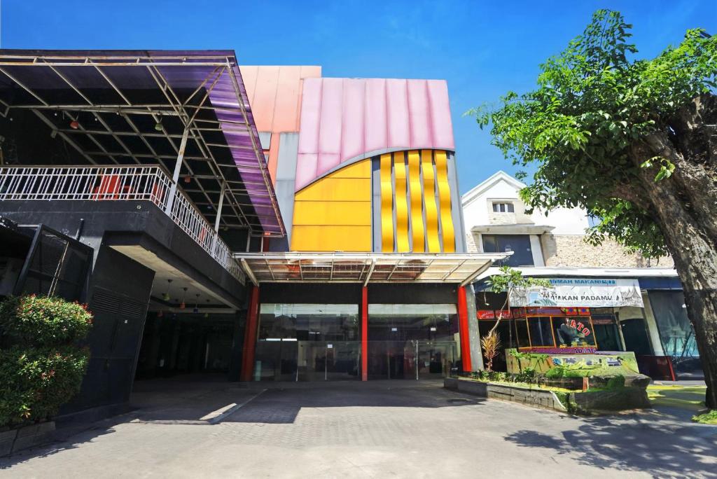a building with a colorful facade with a tree at Townhouse Oak Malang near ITN Malang formerly Fariz Hotel Singosari in Malang
