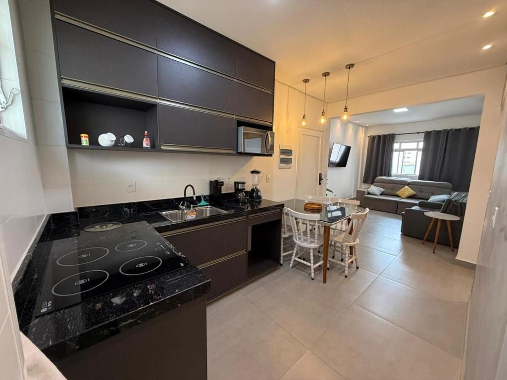 a kitchen and living room with a stove and a table at Apê pé na areia in Santos