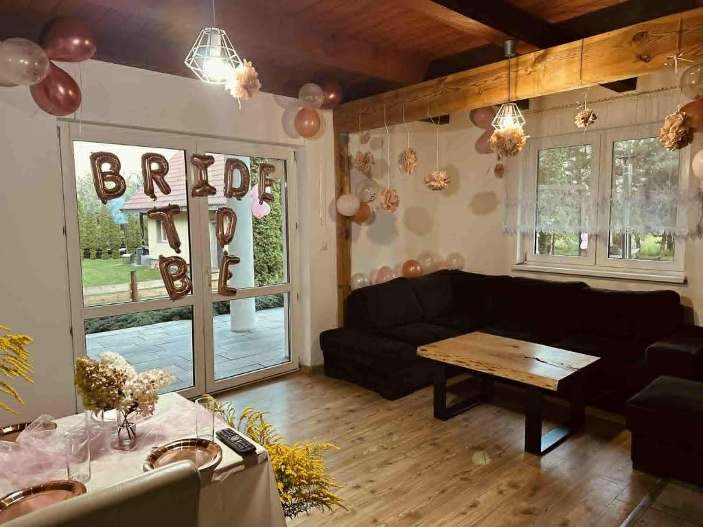 a living room with a black couch and a table at Domek nad Jeziorem z Jacuzzi na Mazurach 10os in Jedwabno