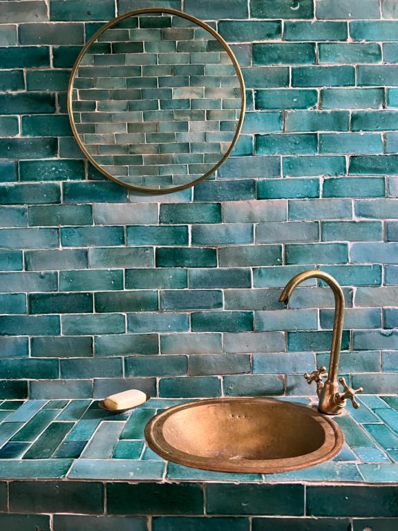a bathroom sink with a mirror on a brick wall at Turquoise Brick Surf House in Essaouira
