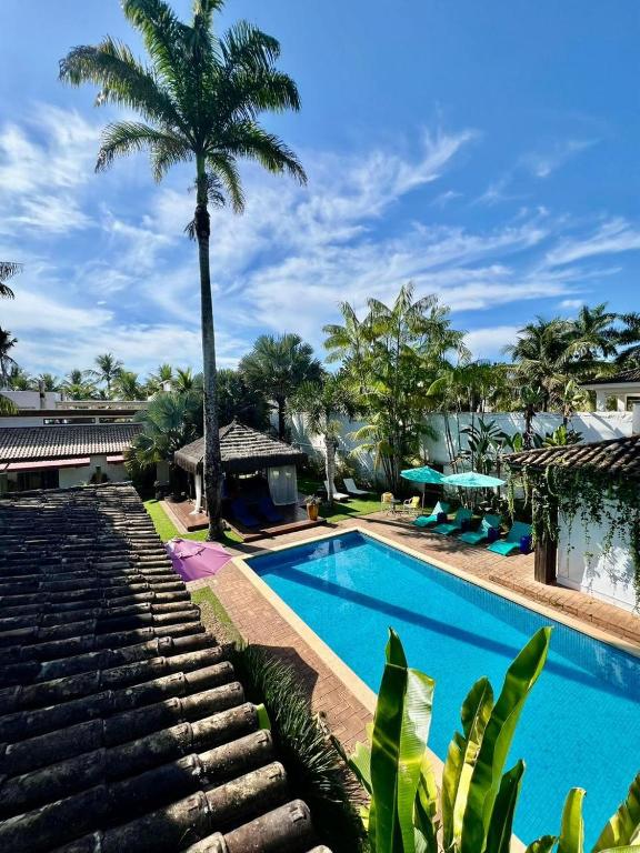 a pool at the resort with a palm tree at Hotel Casa Paradiso Guarujá in Guarujá