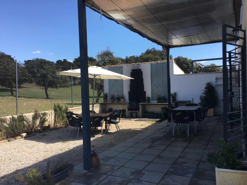 um pátio com um guarda-sol, mesas e cadeiras em Casa Rural Nacimiento del Hueznar - Tomillo 17 em San Nicolás del Puerto