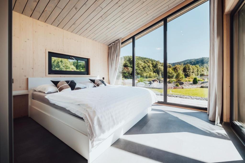 a bedroom with a large bed and large windows at Na Kameni in Vsetín
