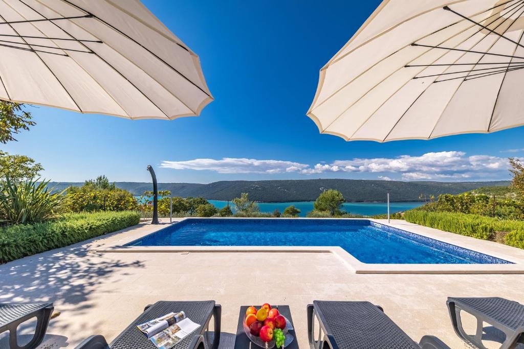 a swimming pool with an umbrella and a table and chairs at Seaview Pool House Mytilus - Happy Rentals in Trgetari