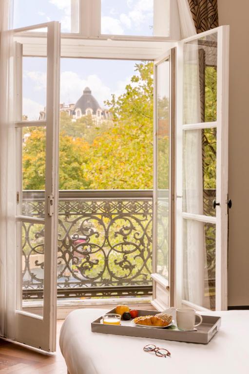 una bandeja de comida sentada en una cama frente a una ventana en Appart'City Collection Nîmes Arènes, en Nimes