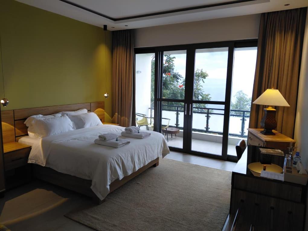 Una habitación de hotel con una cama y una ventana grande. en RUBONA HILL Lodge, en Gisenyi