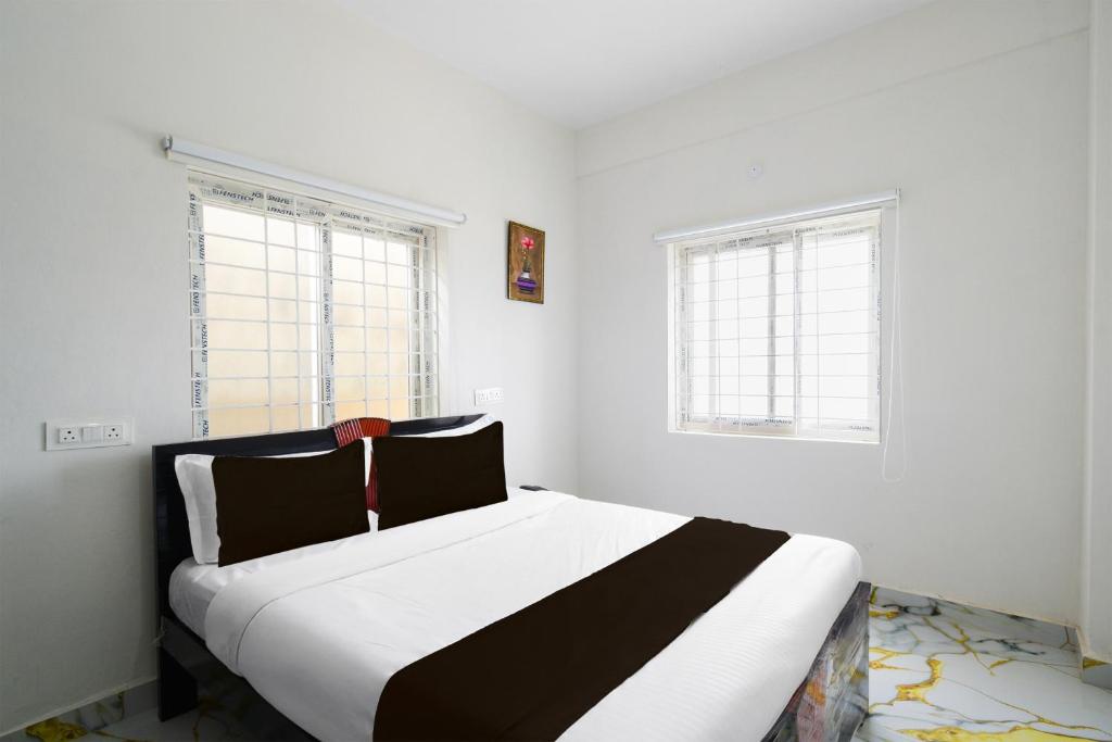 a bedroom with a large white bed with two windows at SPOT ON GN luxury Suits in Hyderabad