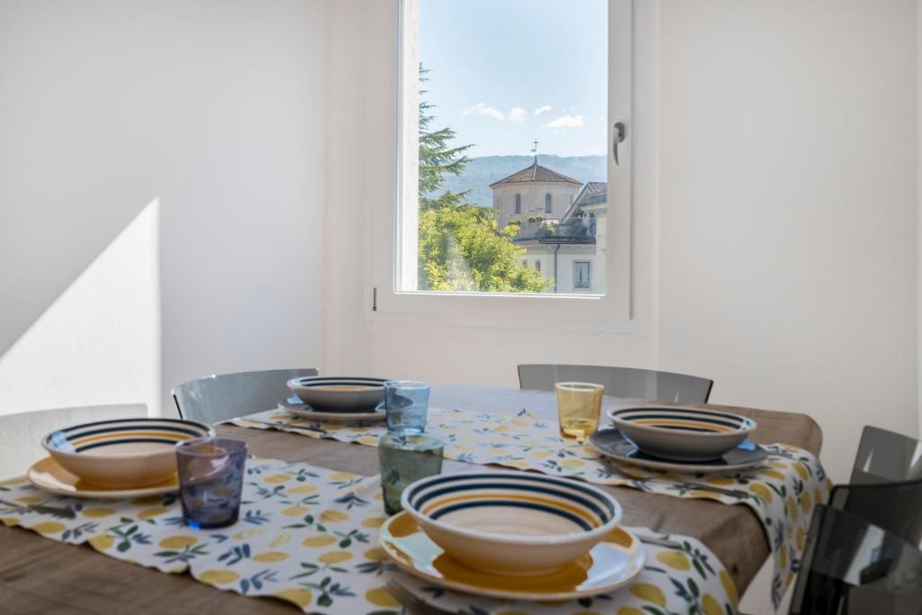 - une table à manger avec des assiettes et des bols dans l'établissement GuestHost - Piazza Castello Belluno Central Dream, à Belluno
