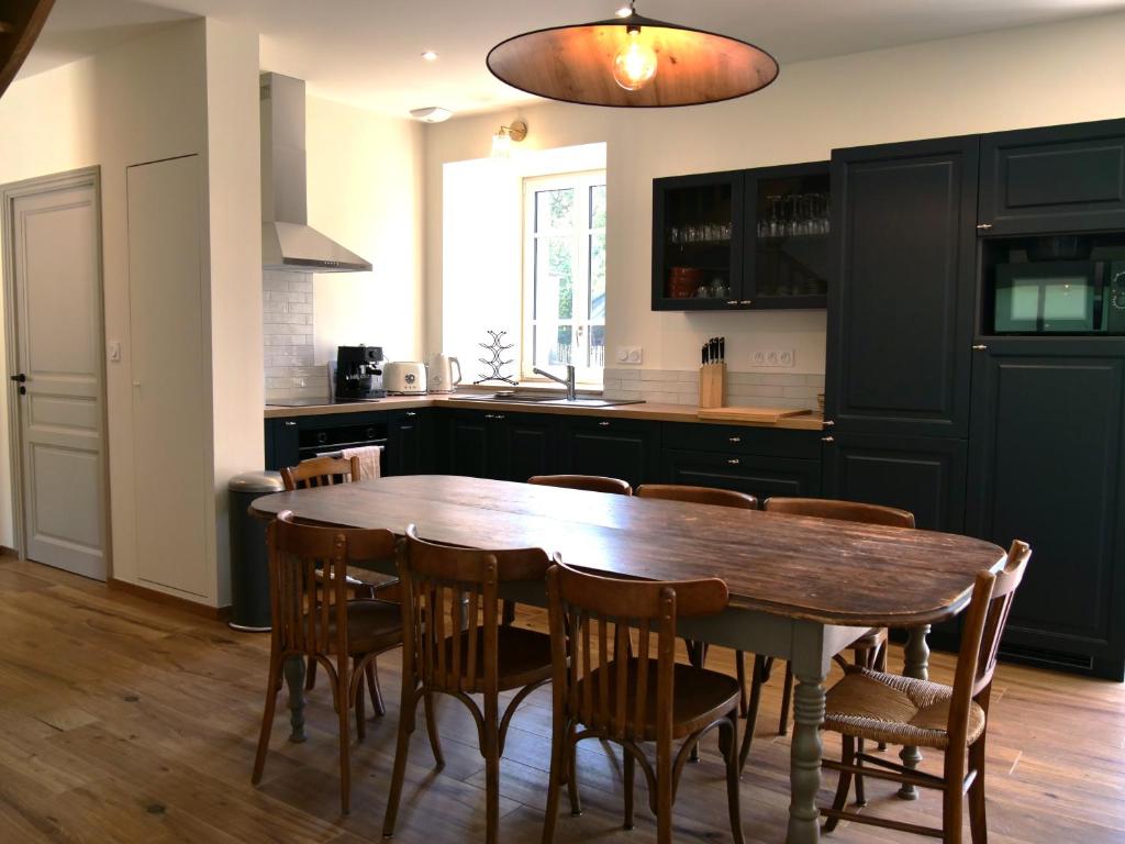 cocina con mesa de madera y sillas de madera en A l'abri des marées - Maison de charme dans le parc du Domaine du Cloitre, en Pléneuf-Val-André