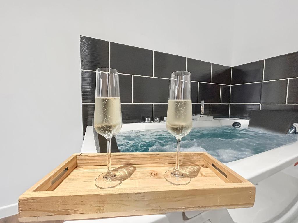 - deux verres à vin sur un plateau en bois dans une baignoire dans l'établissement Balnéo privée, Cinéma, Fibre & Patio, à Tourcoing