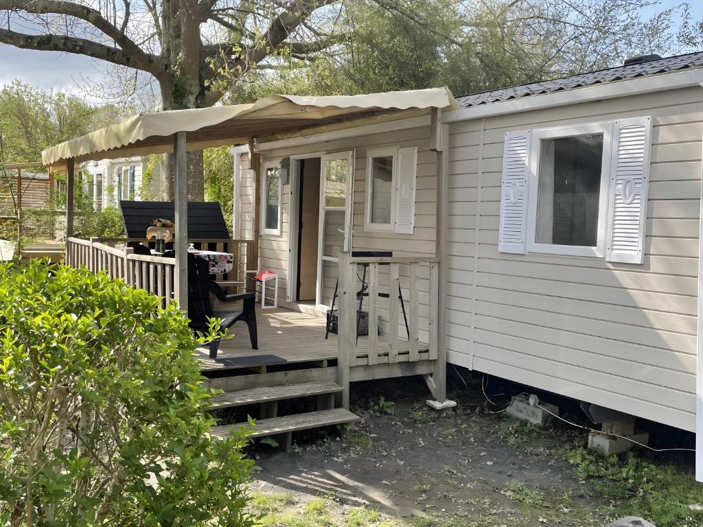 a tiny house with a porch and a deck at Cosy Mobil-Home climatisé in Aureilhan