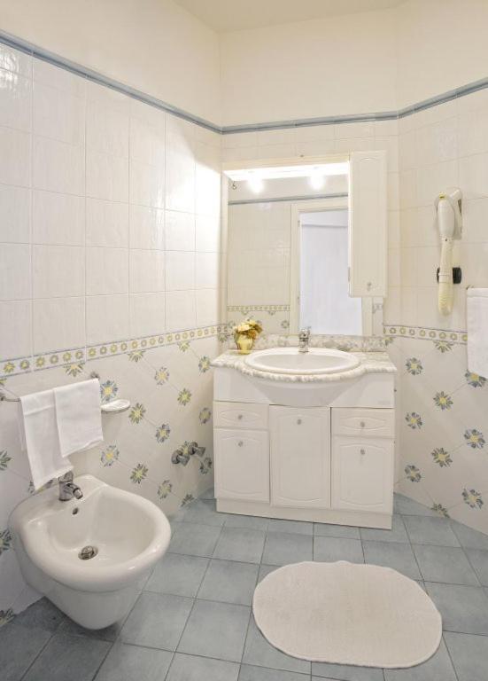 un bagno bianco con lavandino e WC di Albergo Villa Hibiscus a Ischia