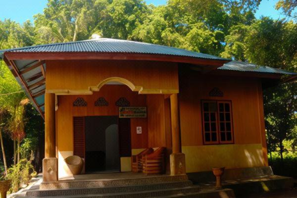 a small orange house with a porch and trees at Evelin Cottage in Ngurblut