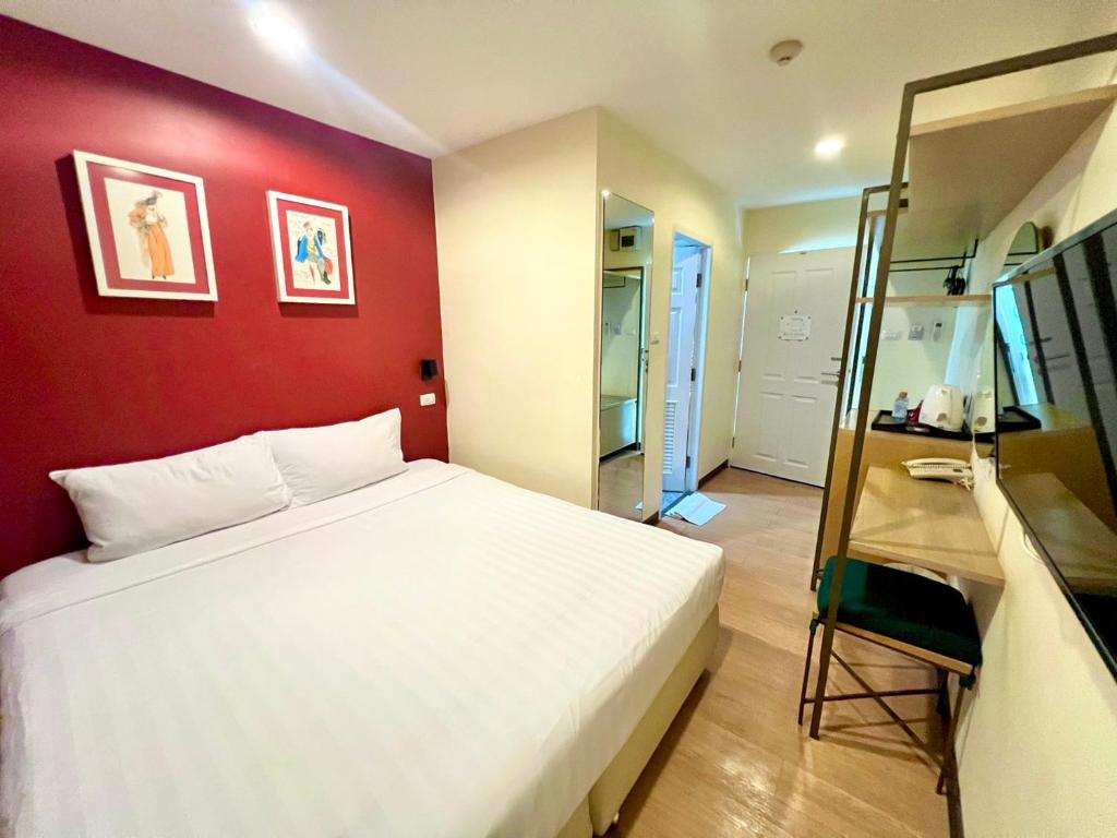 a bedroom with a white bed and a red wall at Klean Residence Hotel in Bangkok