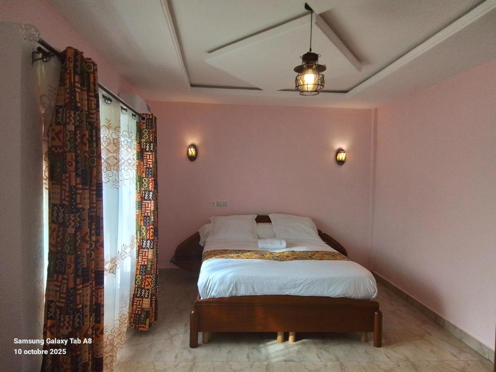 a bedroom with a bed in a room with pink walls at Villa le chant des Alizés 