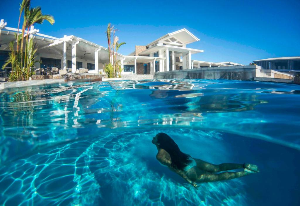 a mermaid swimming in a pool in front of a house at Taumeasina Island Resort in Apia