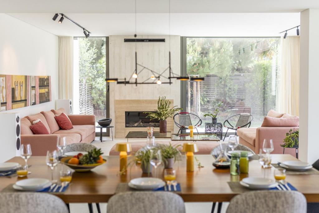 a living room with a wooden table and chairs at Troia Design Villa by CadenzaLux in Troia
