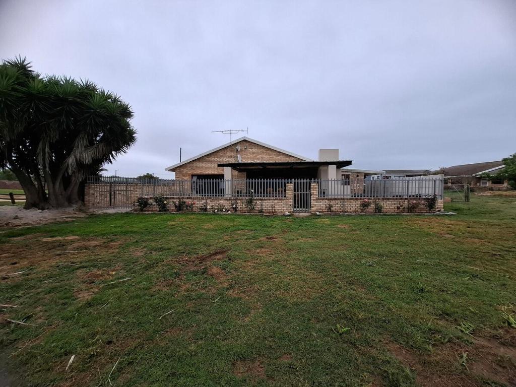a house with a fence and a grass field at Addo River Den 4 in Gqeberha