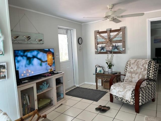 a living room with a flat screen tv and a chair at Gulf Front Cottages in Englewood