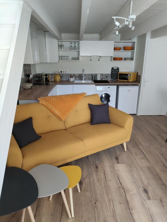 a living room with a couch and a kitchen at Chez madame Hulotte in Saint-Nazaire