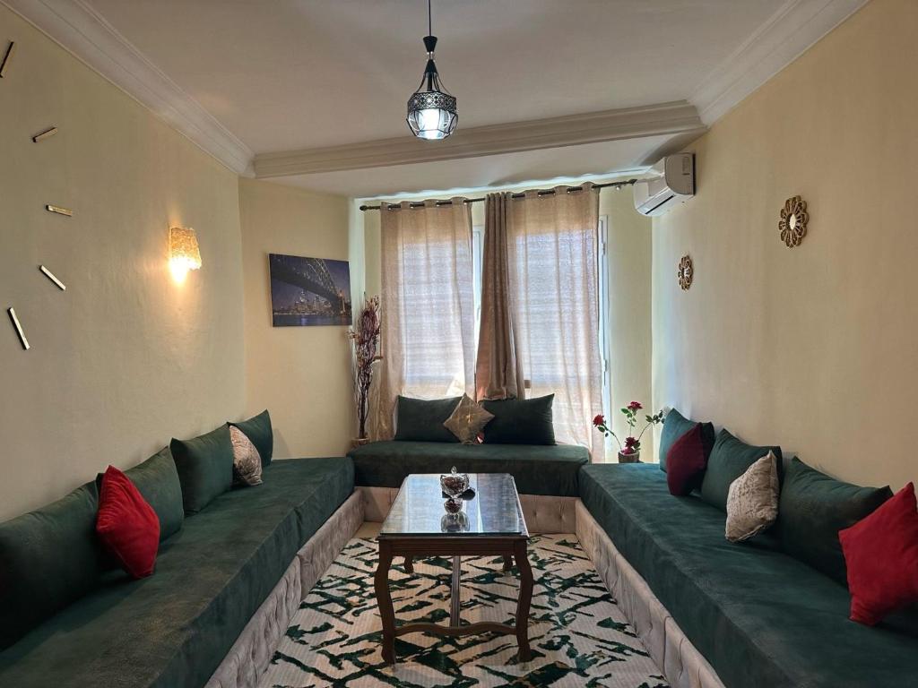 a living room with green couches and a table at Location Appartement tangier malabata in Tangier