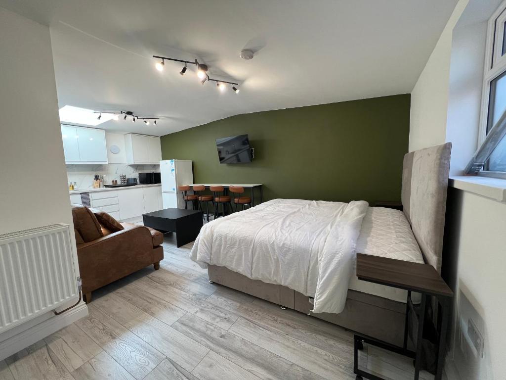 a bedroom with a bed with a green wall at Little studio flat in Southgate
