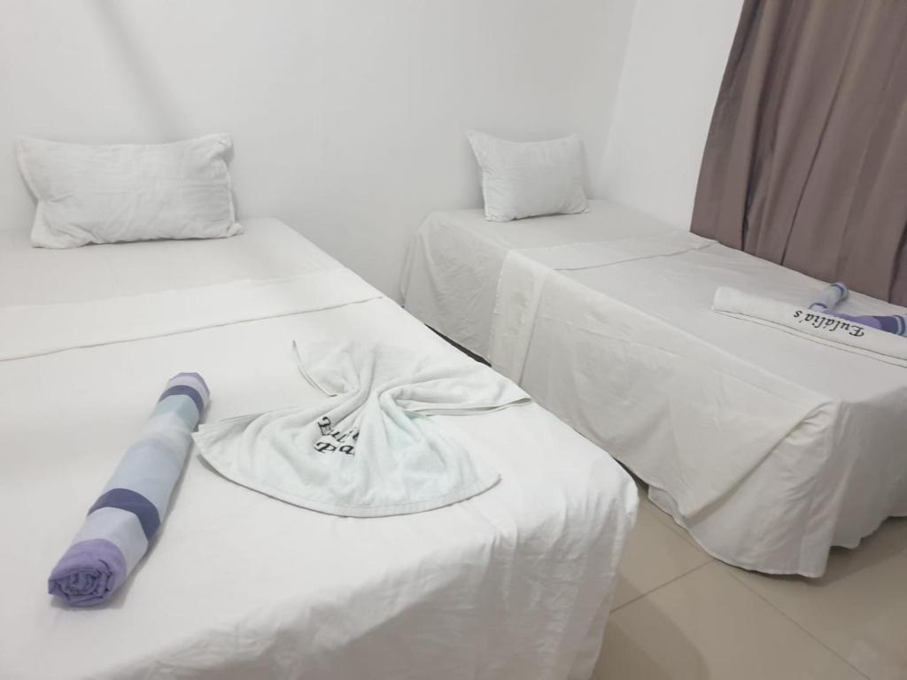 two beds with white sheets and a baseball cap on them at Eulália villa in Vila Praia Do Bilene