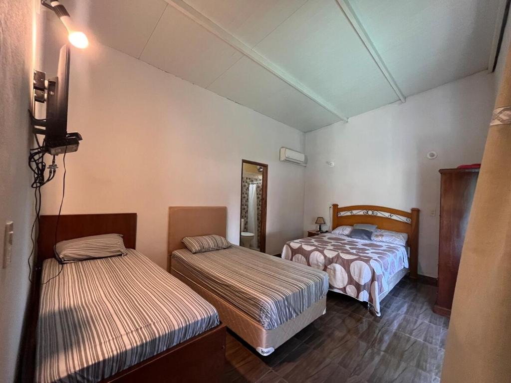 Una habitación con dos camas y un televisor. en Posada El Encuentro, en Atyrá