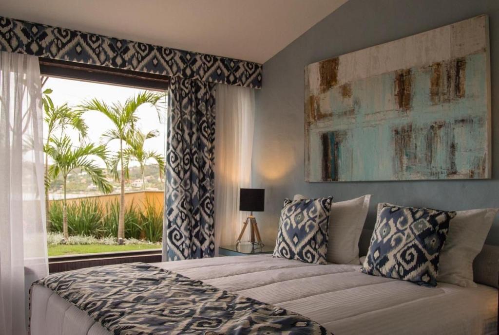 a bedroom with a bed and a large window at Mar Búzios inn in Búzios