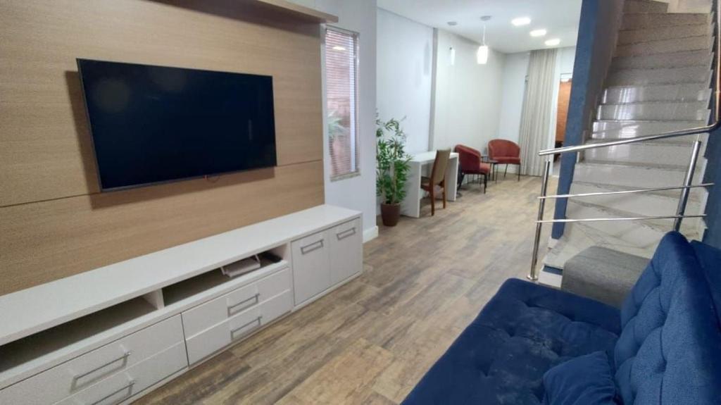 uma sala de estar com uma TV e um sofá azul em Casa c/ Churrasqueira a 550 m da Praia PDD0572 em Piçarras