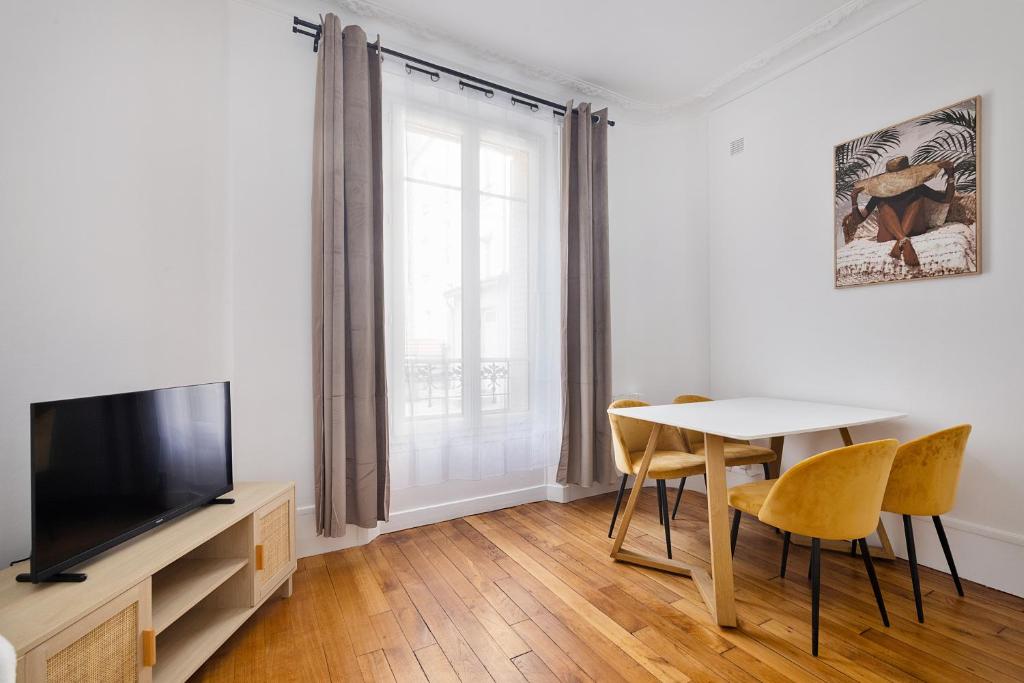 Una sala de estar con una mesa y un televisor. en 3P Cosy proche Paris La Défense Fondation LV, en Suresnes