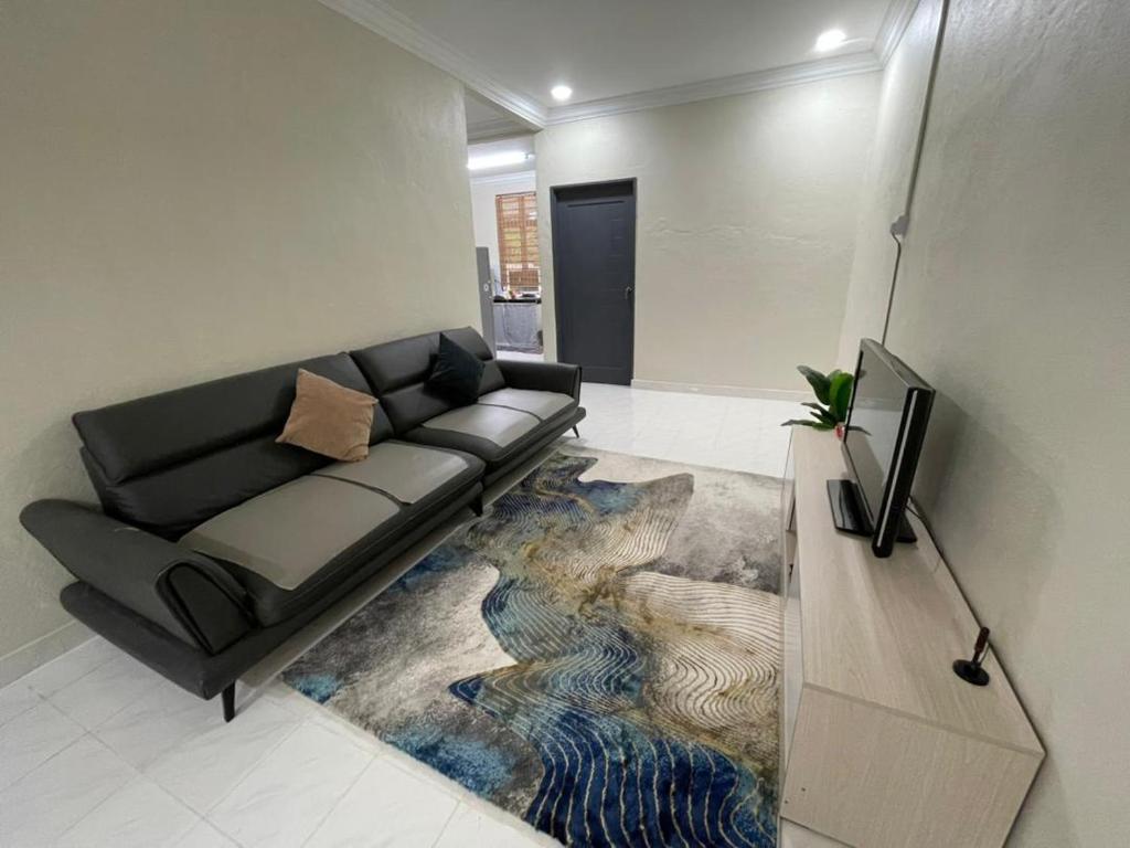- un salon avec un canapé noir et un tapis dans l'établissement AM Homestay, à Kota Bharu