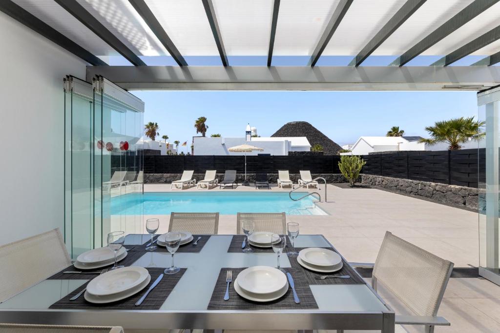a dining room with a table and a swimming pool at Villas Volcan in Playa Blanca