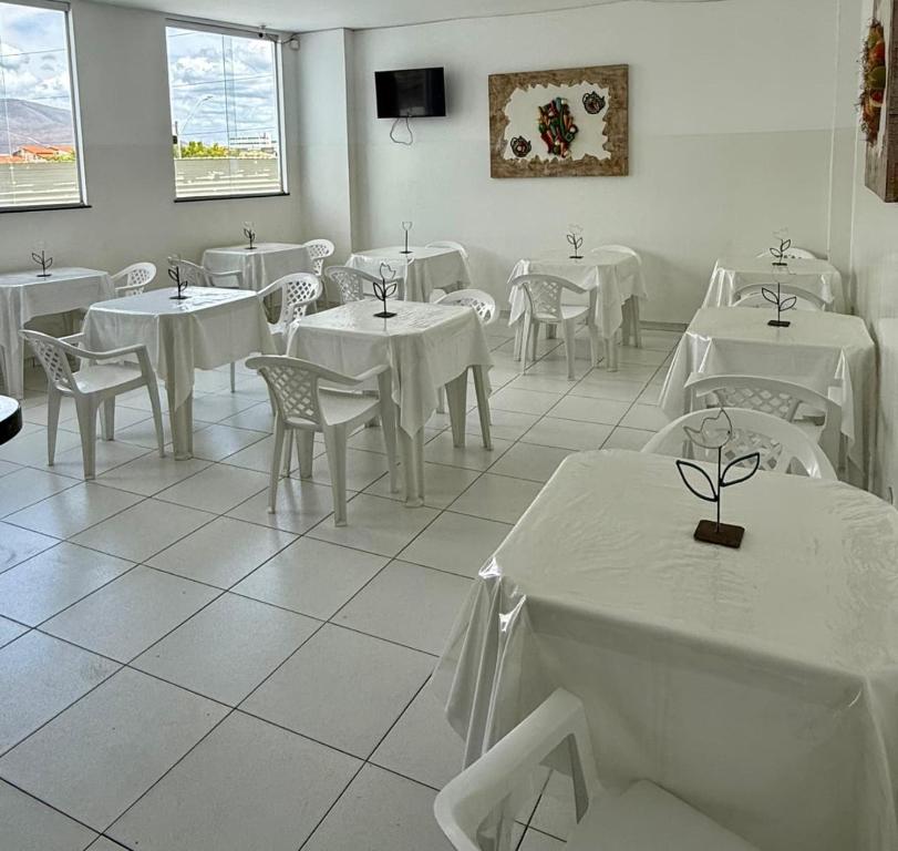 Un comedor con mesas y sillas blancas. en Hotel Ideal, en Jequié