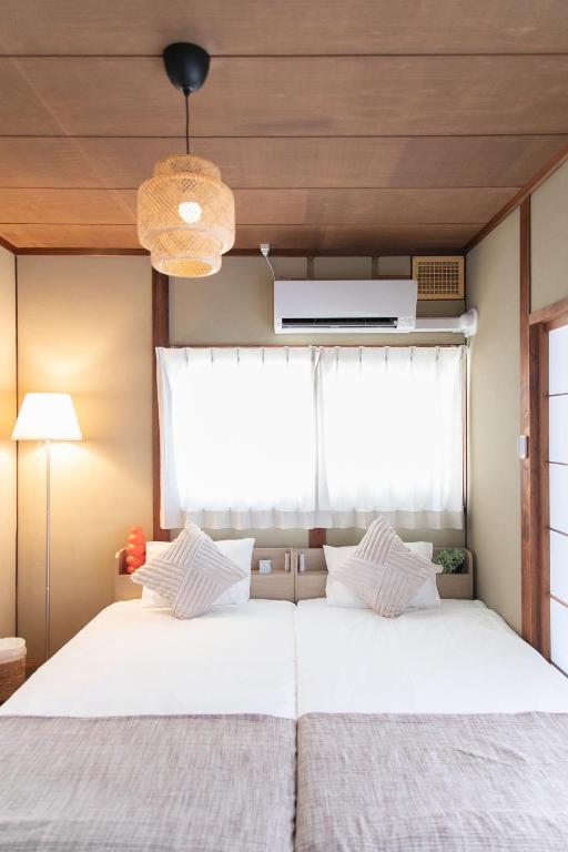 a bedroom with a large white bed with a window at Ao by Perch Japan in Nagoya